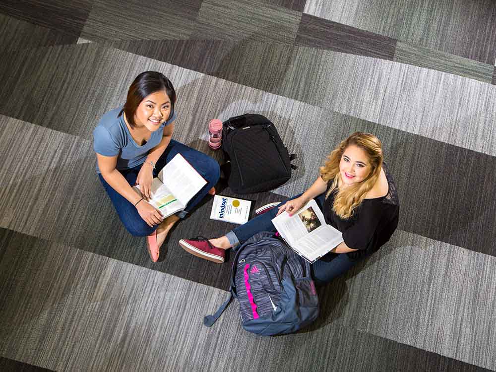 Two San Jacinto College students sitting on floor studying