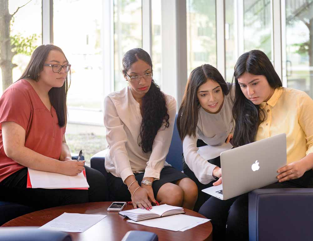 Pathway students sitting around laptop computer.